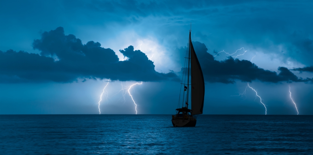 Sailing yacht in a stormy weather with lightning in the distance